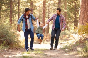 Gay Male Couple With Daughter Walking Through Fall Woodland